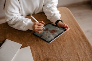 a person sitting at a table writing on a tablet