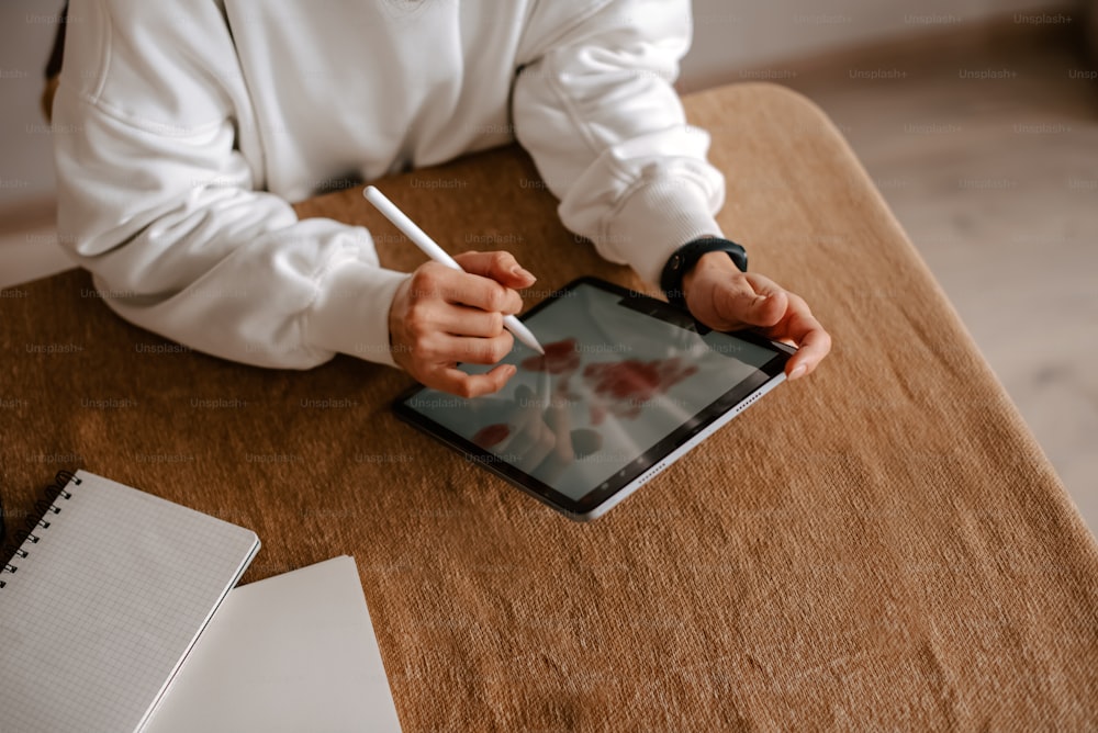 a person sitting at a table writing on a tablet