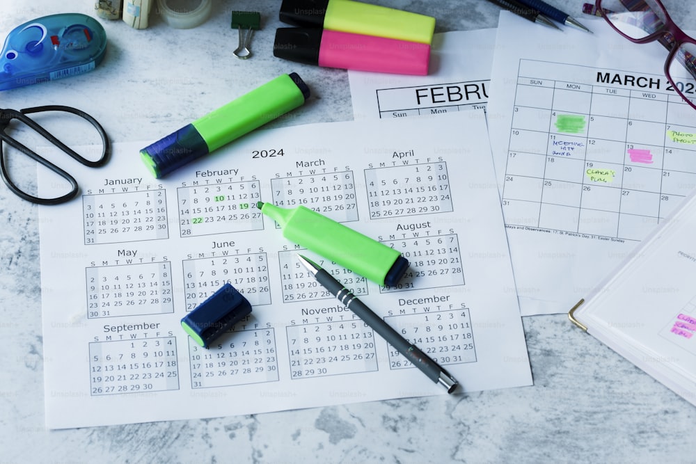 un escritorio con un calendario, bolígrafos y otros suministros de oficina