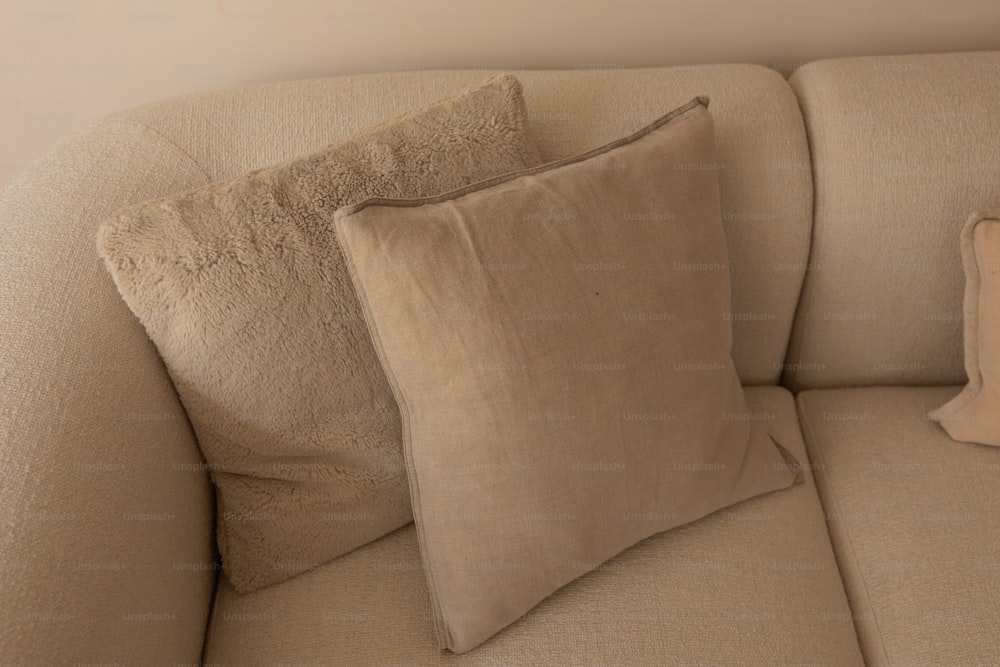 a beige couch with two pillows on top of it