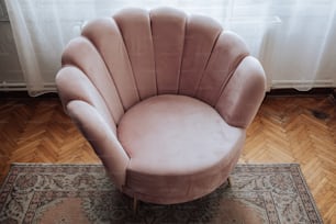 Ein rosafarbener Stuhl sitzt auf einem Holzboden