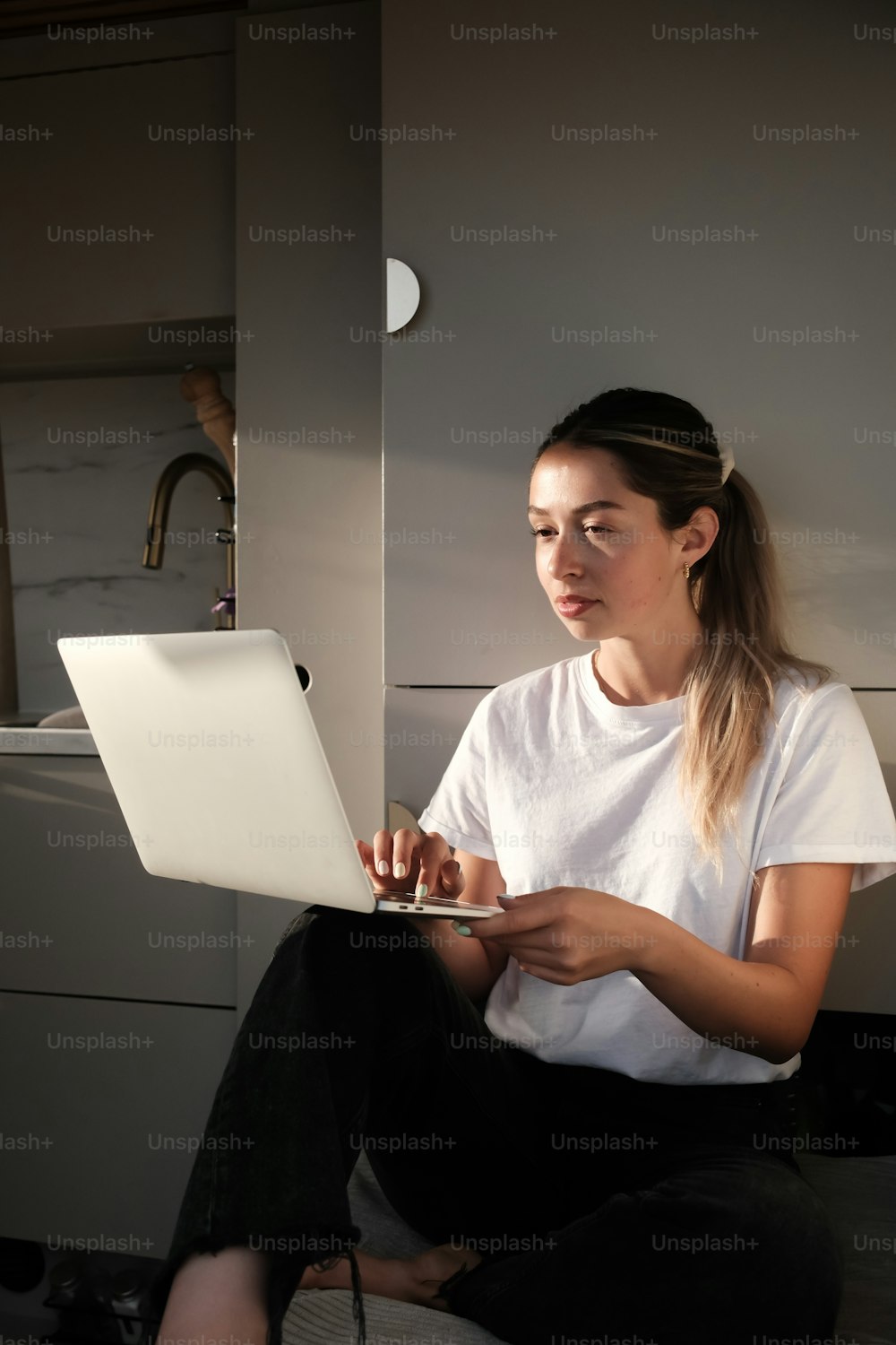 a woman sitting on a bed using a laptop computer