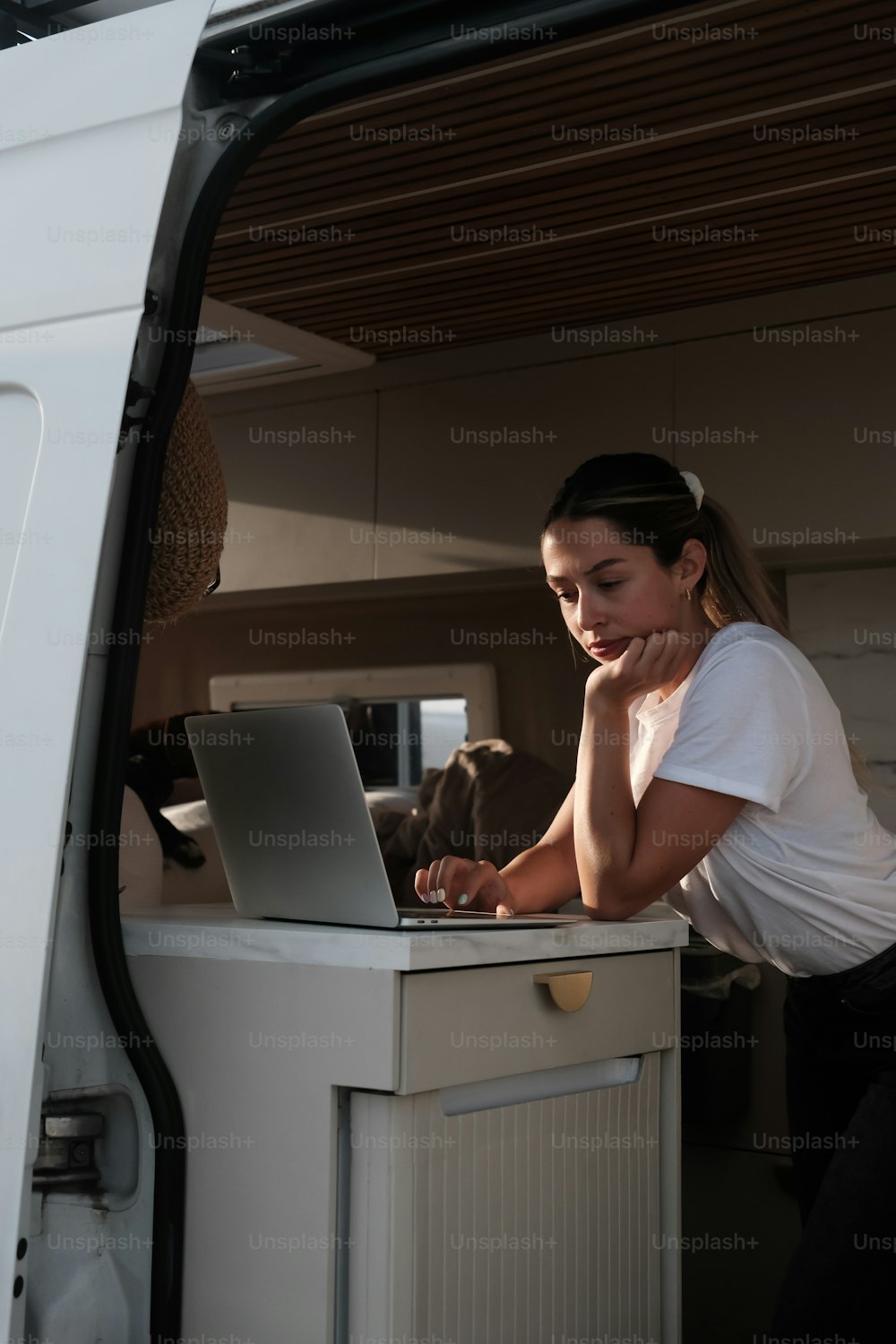 a woman sitting in the back of a van using a laptop computer