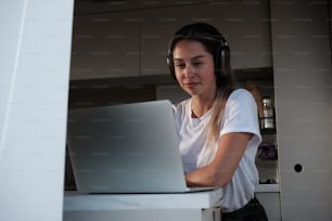 a woman with headphones on looking at a laptop
