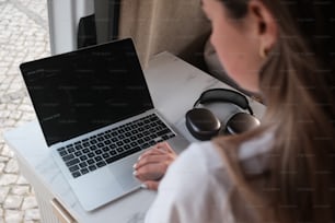 uma mulher sentada em uma mesa com um laptop e fones de ouvido