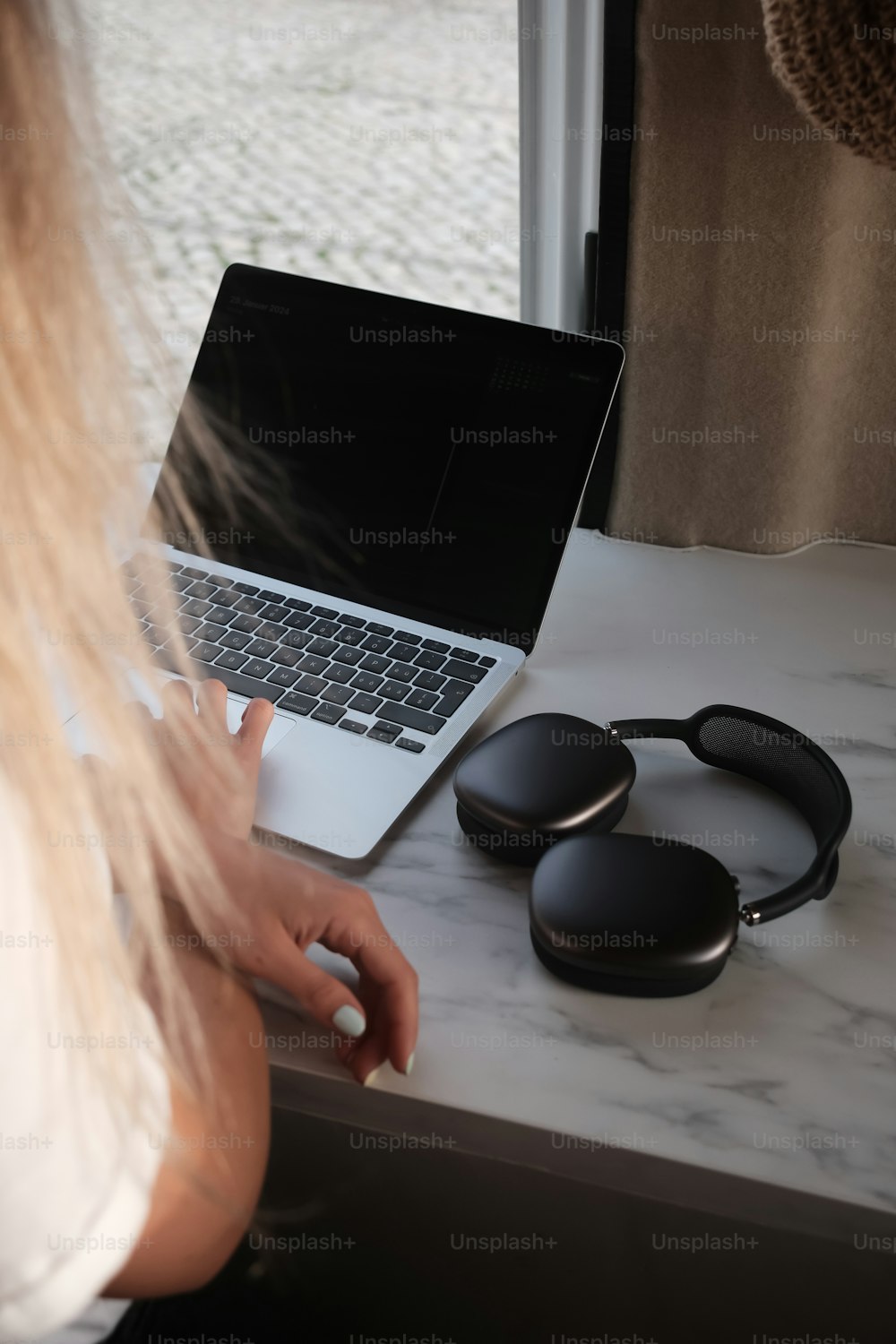 a woman sitting at a table with a laptop and headphones