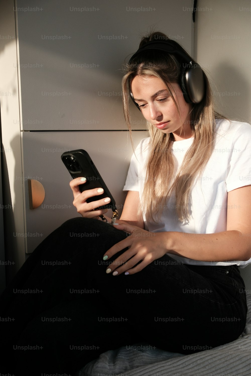 una donna seduta su un letto che usa un telefono cellulare
