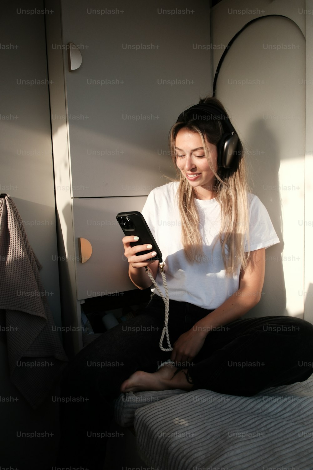 a woman sitting on a bed with headphones on