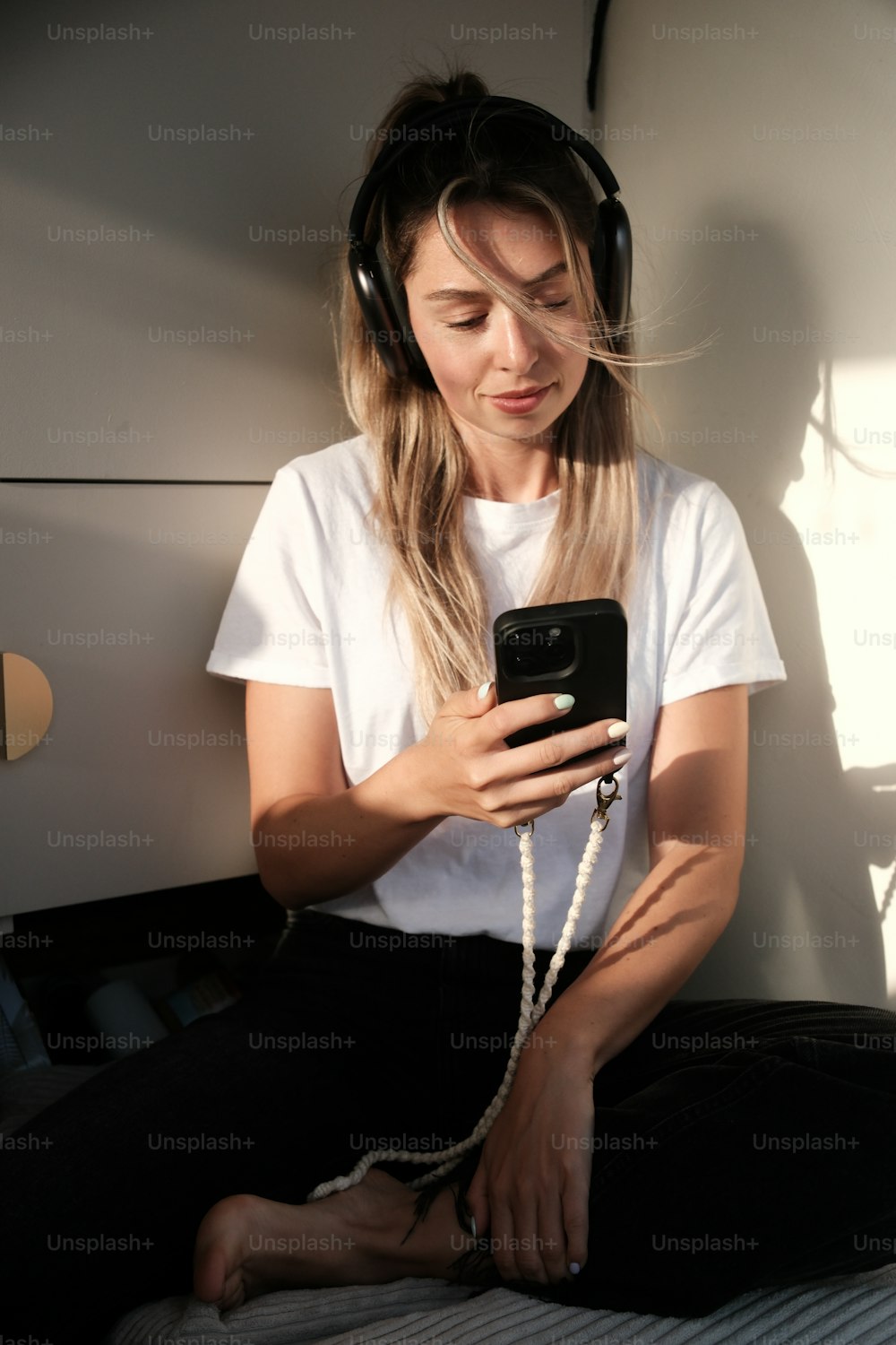 a woman sitting on a bed wearing headphones