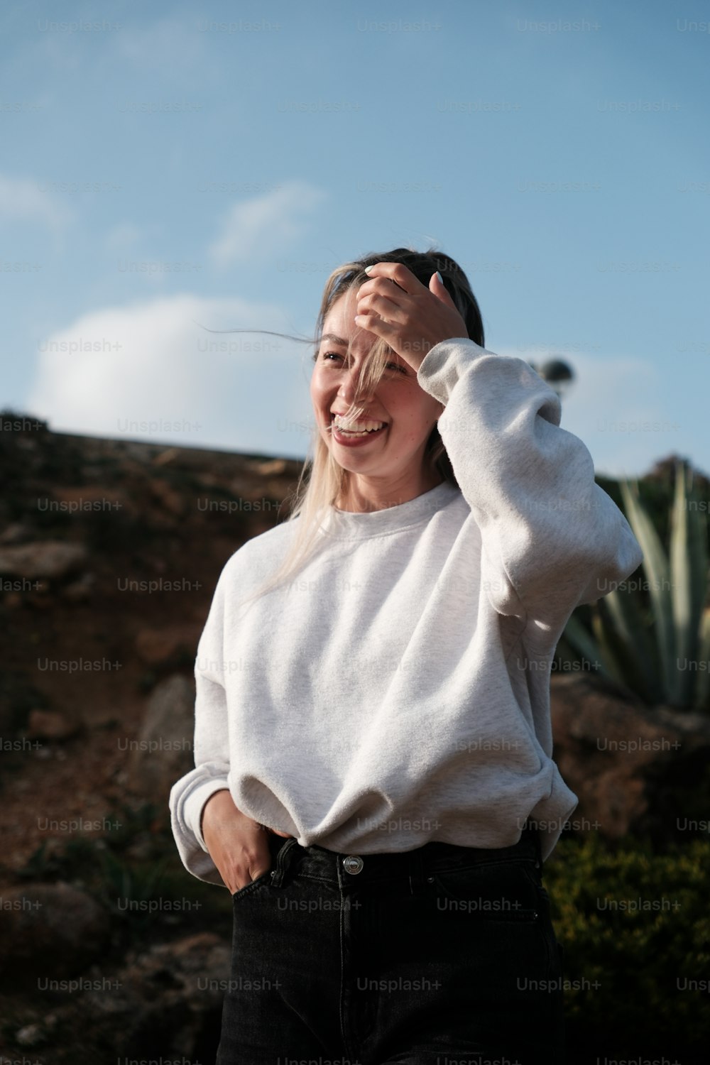 una donna in piedi davanti a un cactus con le mani sulla testa