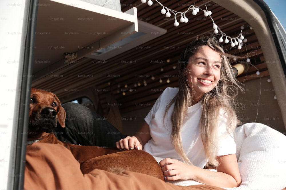 a woman sitting in the back of a truck with a dog