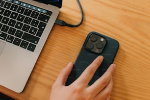 a person using a cell phone next to a laptop