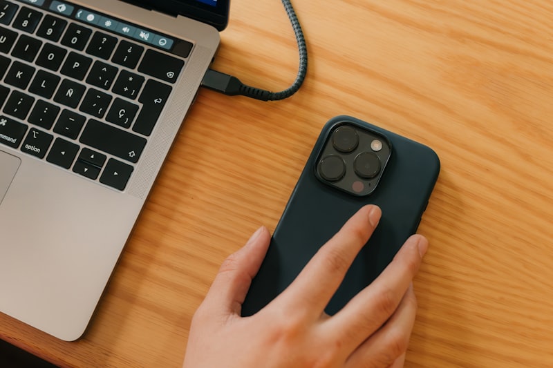 a person using a cell phone next to a laptop