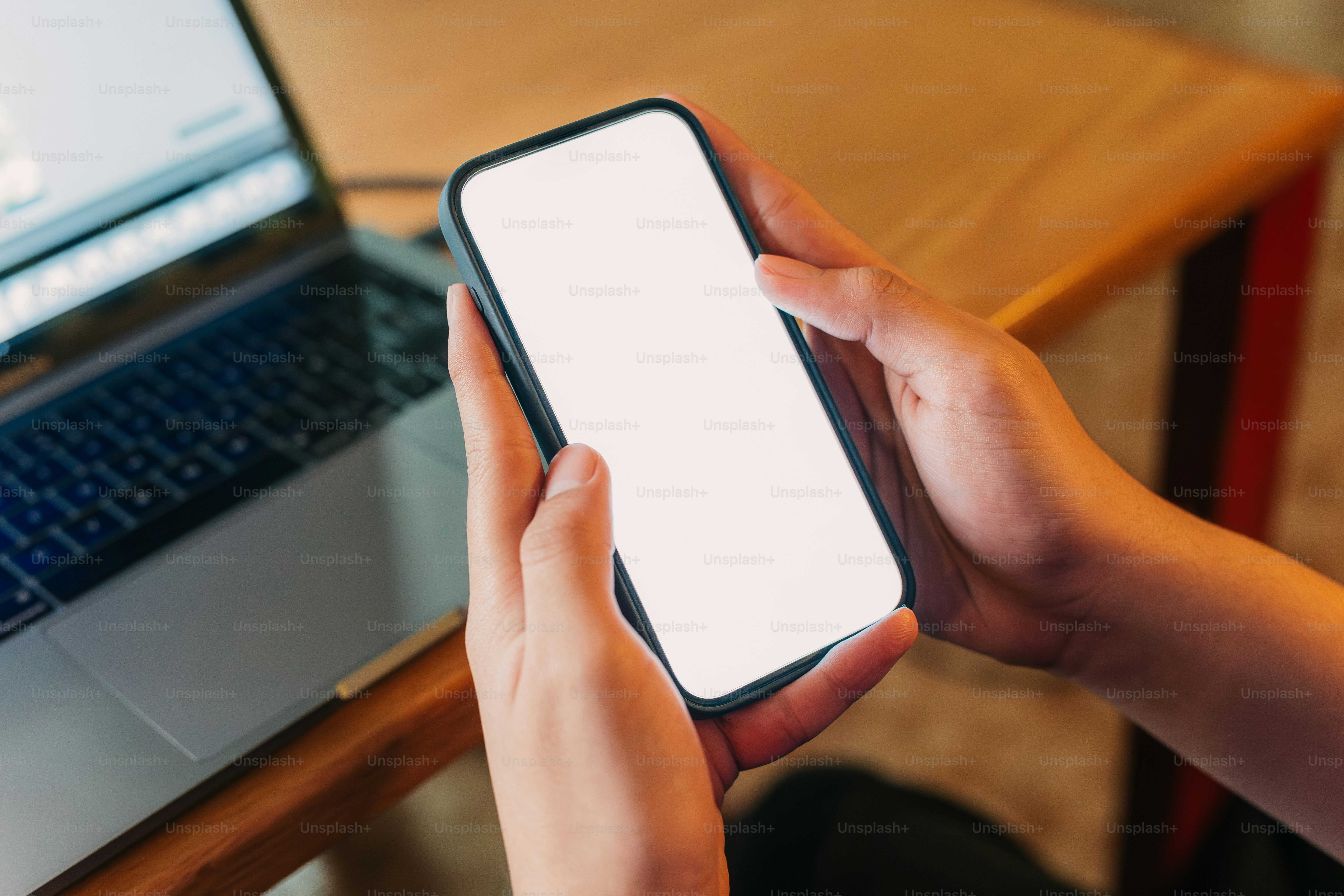 a person holding a cell phone in front of a laptop