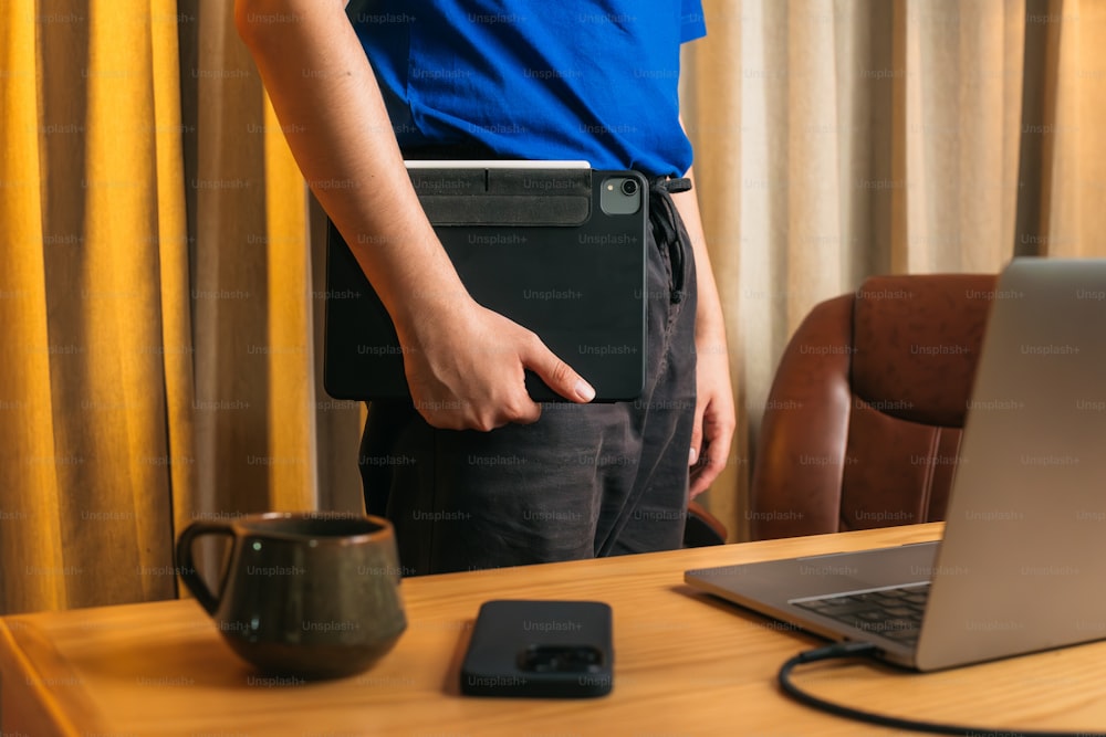 a man holding a laptop in front of a desk