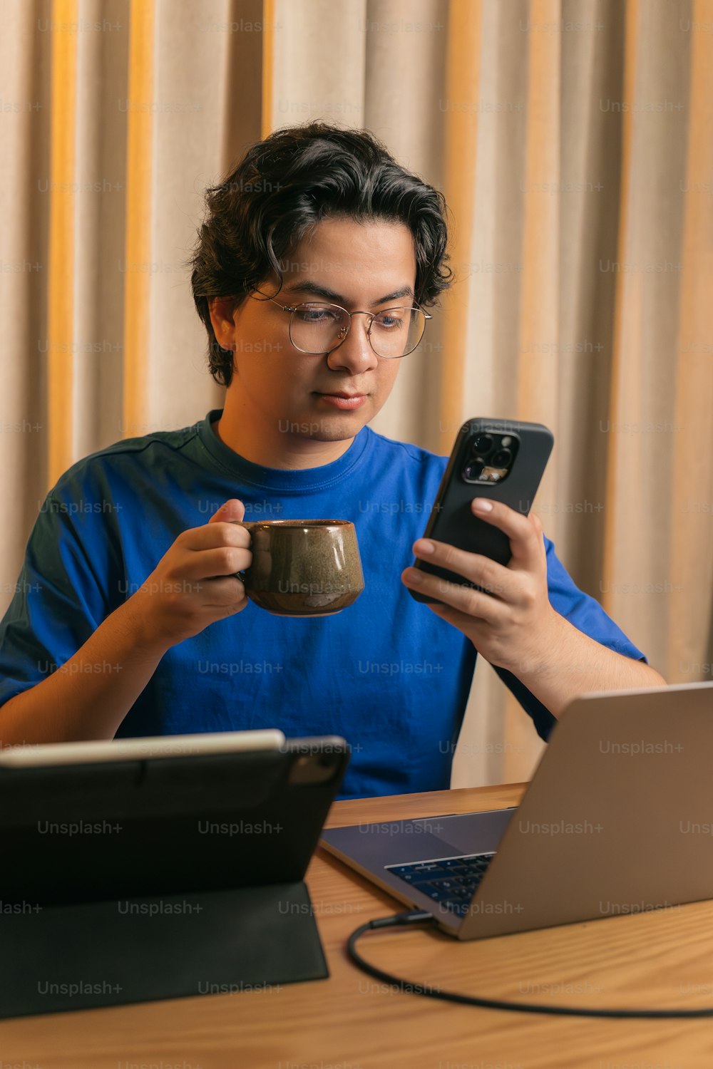 um homem sentado em uma mesa com uma xícara de café na frente de seu laptop