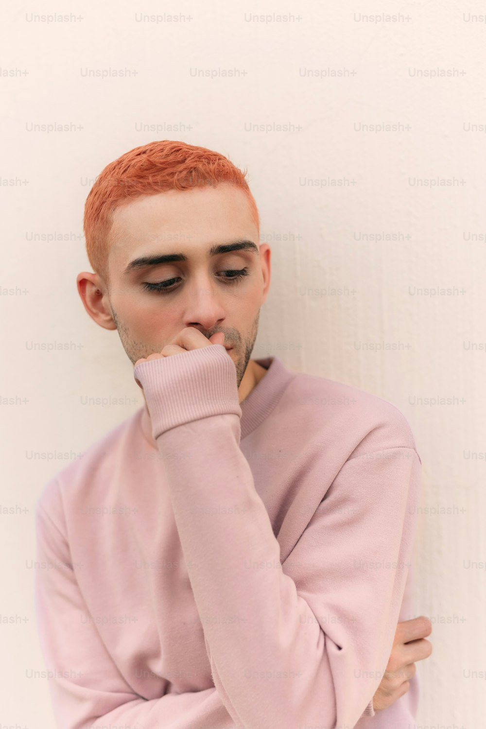 a man with red hair wearing a pink sweater