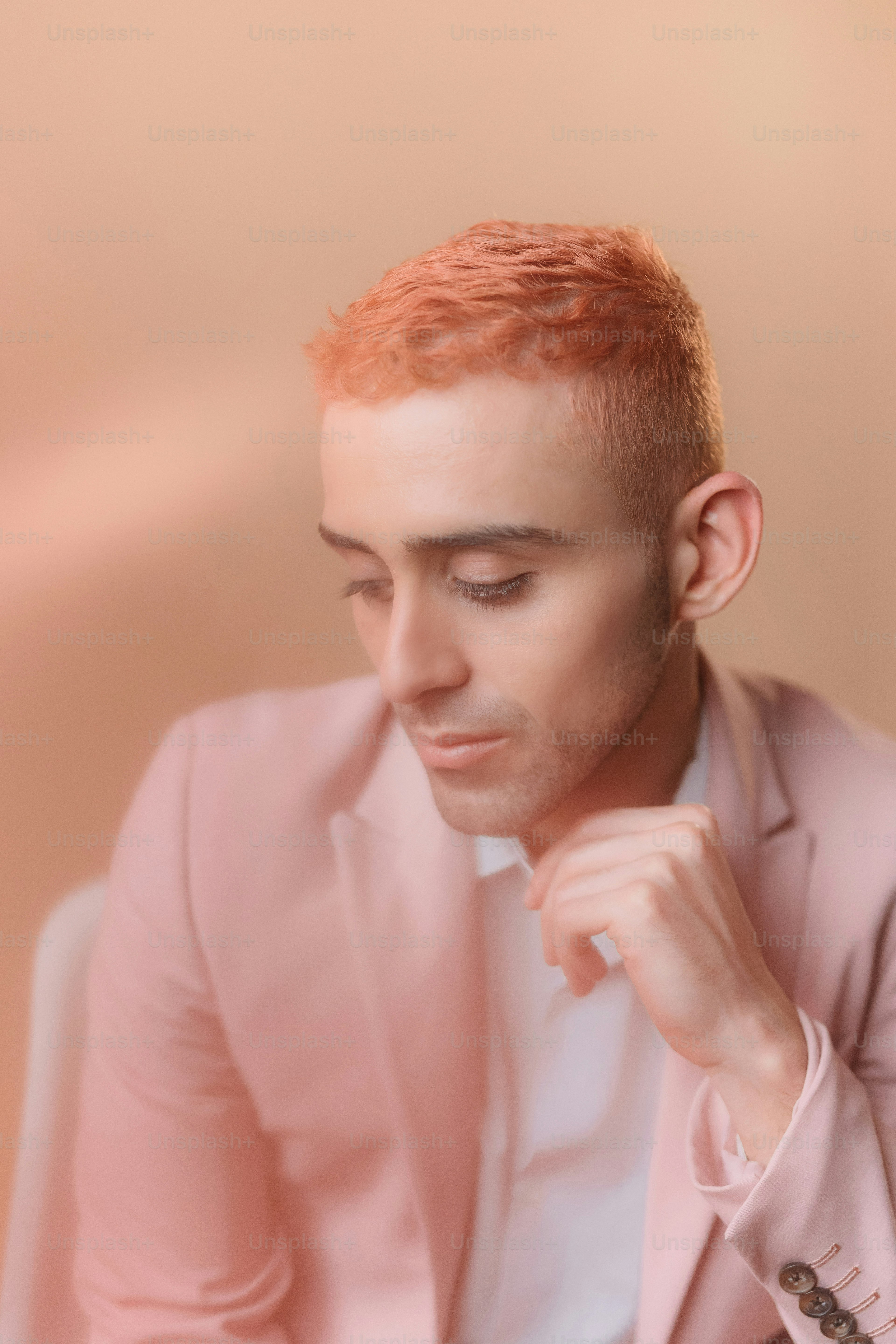 Un homme en costume rose regarde son téléphone portable