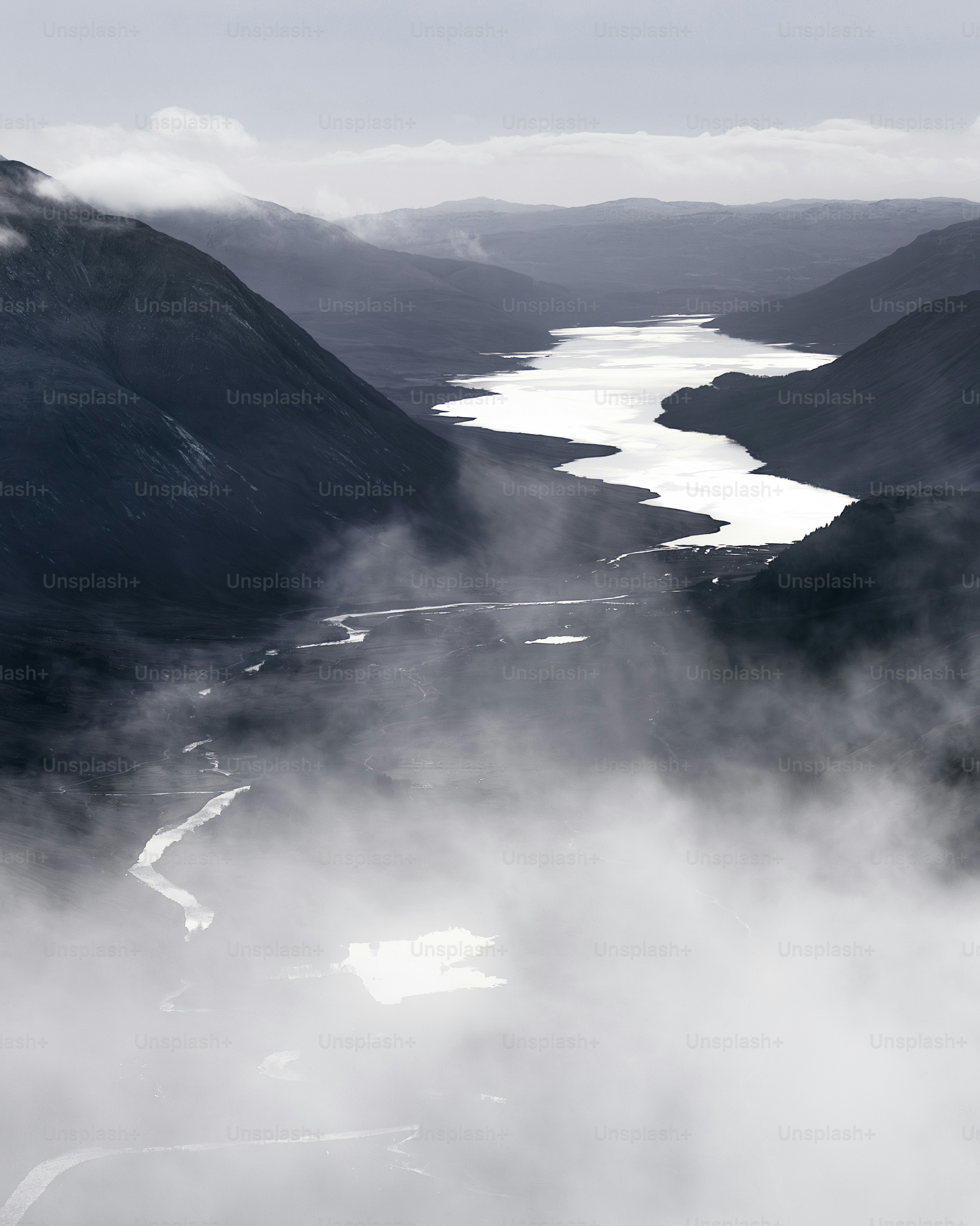 a black and white photo of a river and mountains