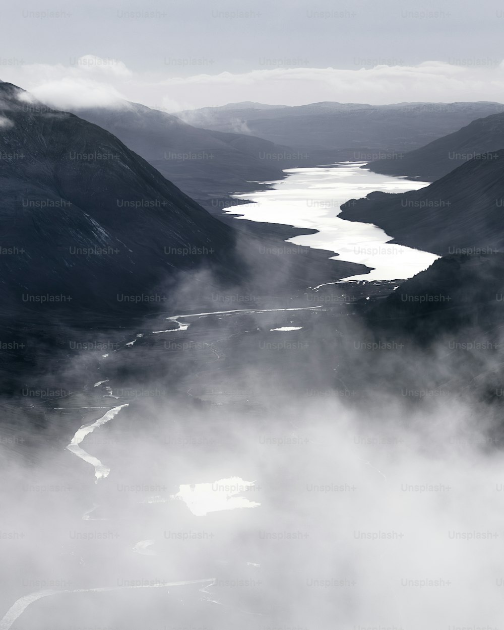 Una foto en blanco y negro de un río y montañas