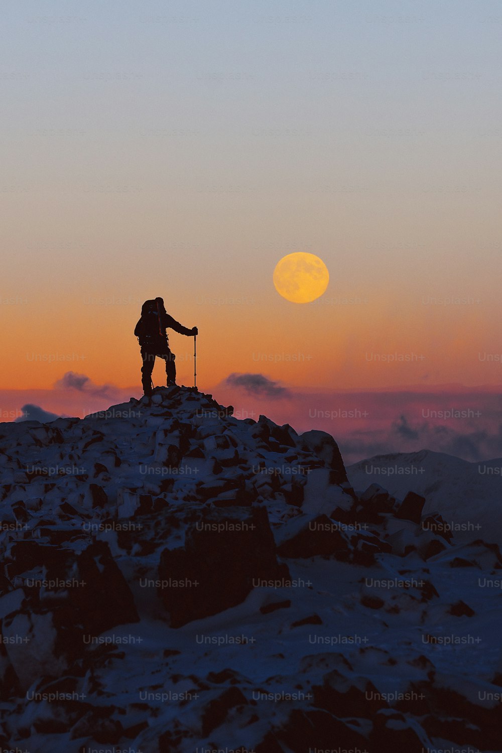 una persona in piedi sulla cima di una montagna innevata