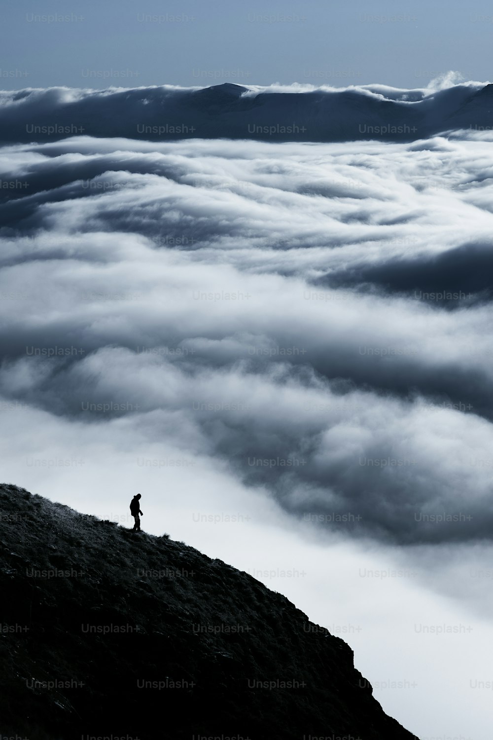 una persona parada en la cima de una montaña por encima de las nubes