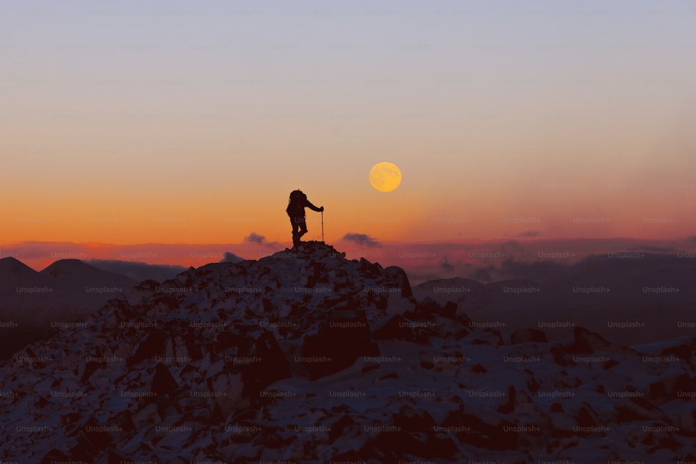 eine Person, die auf dem Gipfel eines schneebedeckten Berges steht