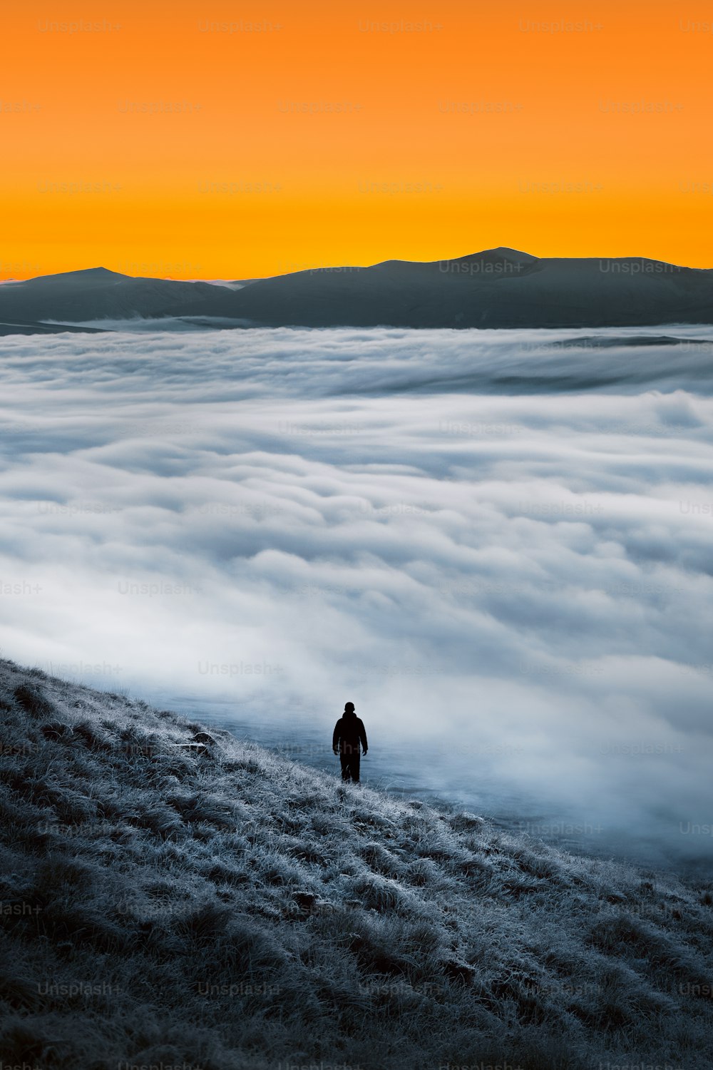 Un hombre parado en la cima de una colina rodeado de nubes