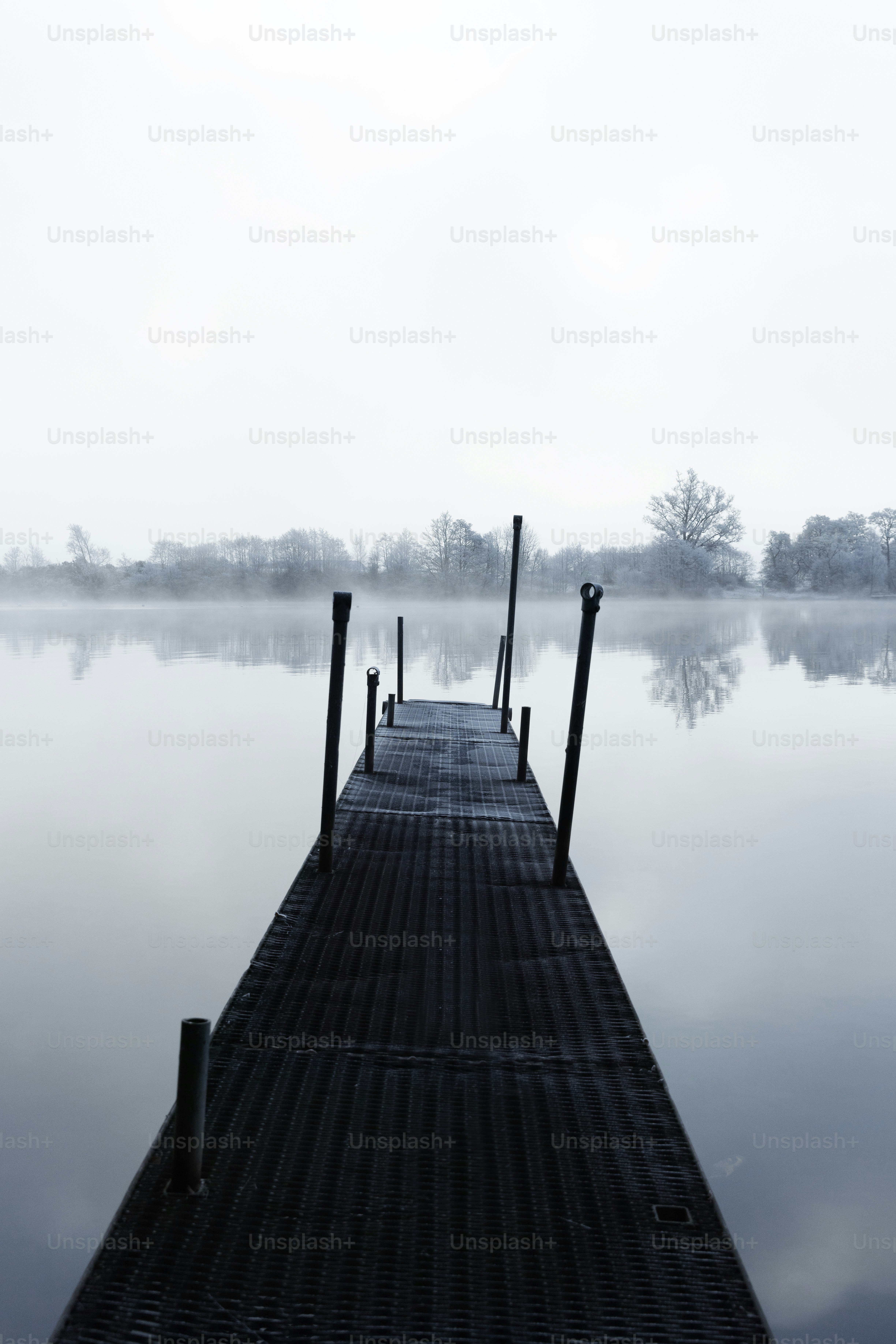 uma doca em um lago no meio de um dia de nevoeiro