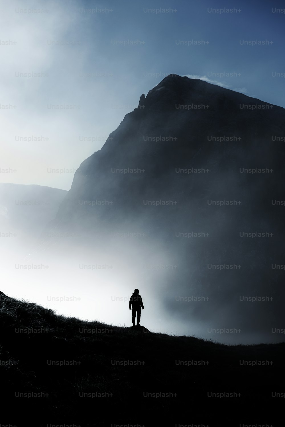 eine Person, die auf einem Hügel mit einem Berg im Hintergrund steht