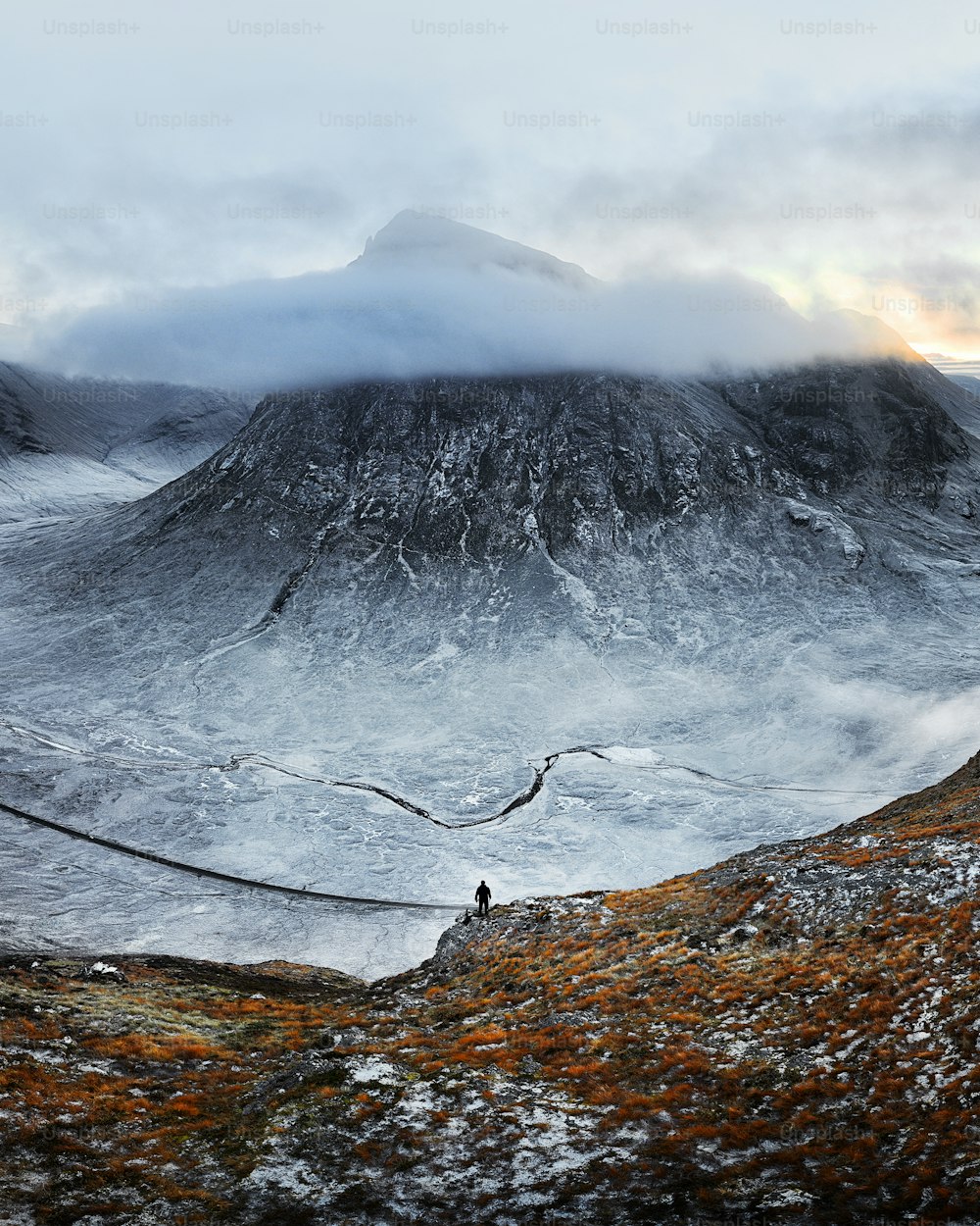 una persona in piedi su una collina con una montagna sullo sfondo