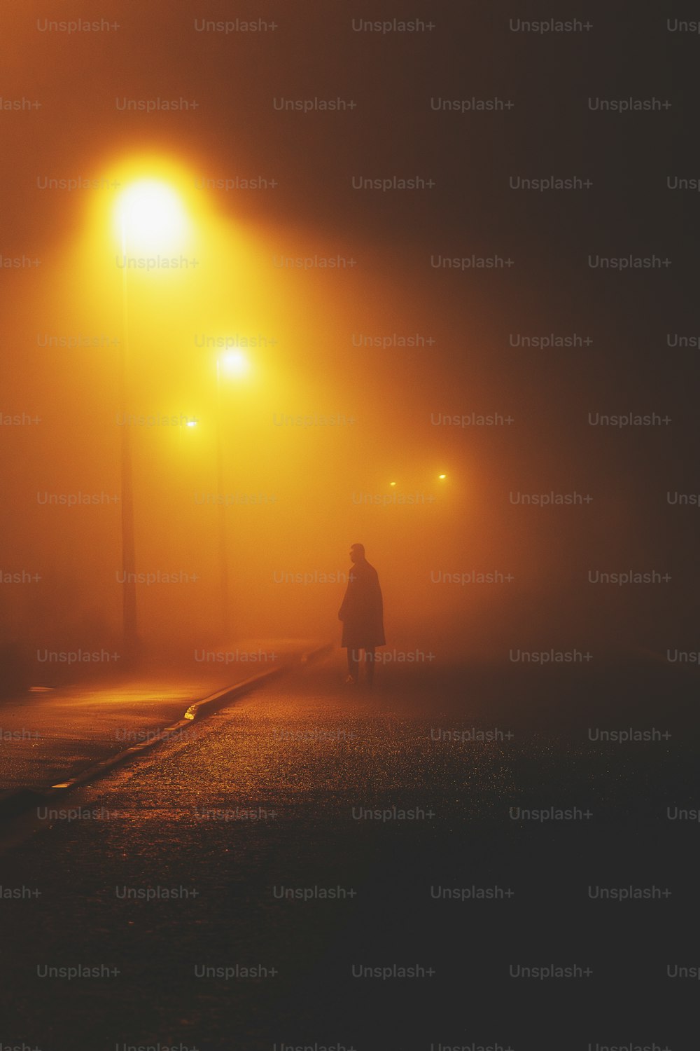 a person walking down a foggy street at night