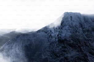 a very tall mountain covered in snow under a cloudy sky