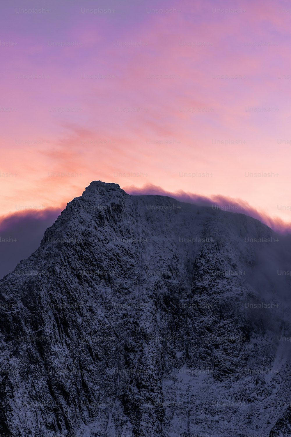 a very tall mountain with a pink sky in the background