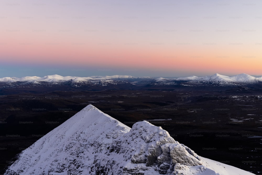 une montagne enneigée avec un coucher de soleil en arrière-plan