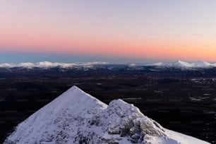 ein schneebedeckter Berg mit einem Sonnenuntergang im Hintergrund