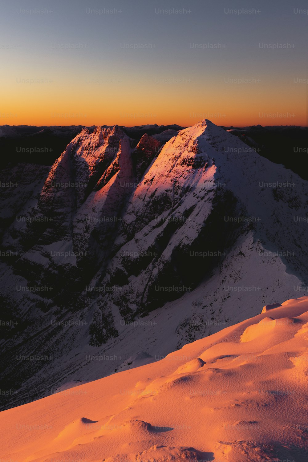 O sol está se pondo sobre uma montanha nevada