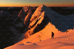 un hombre de pie en la cima de una montaña cubierta de nieve