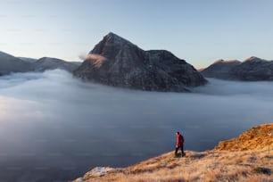 雲に囲まれた山の頂上に立つ男