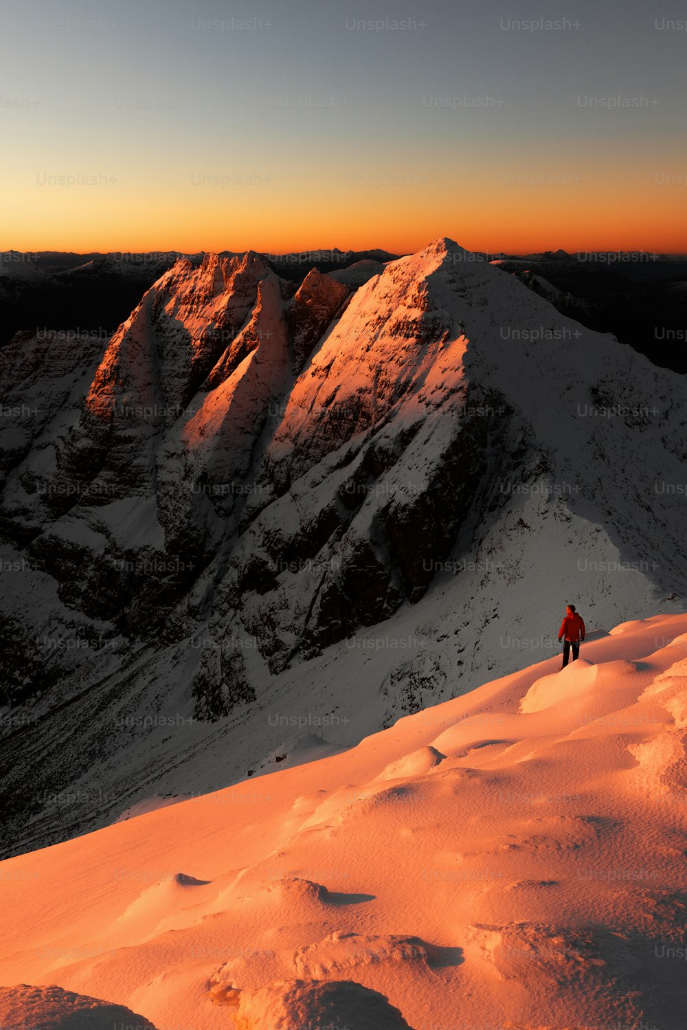 una persona de pie en la cima de una montaña cubierta de nieve