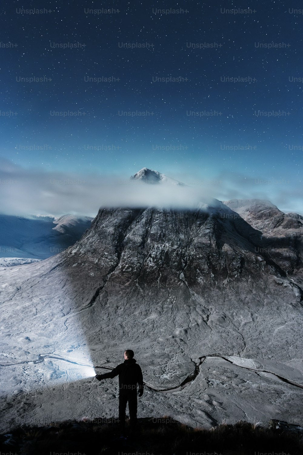 un uomo in piedi sulla cima di una montagna coperta di neve