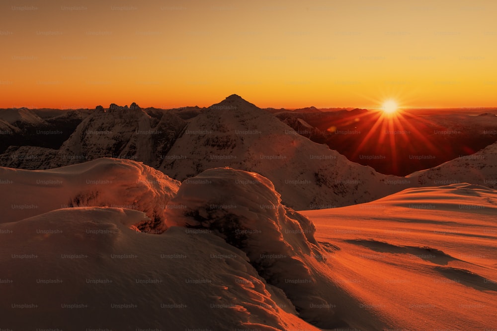 Le soleil se couche sur une chaîne de montagnes enneigées