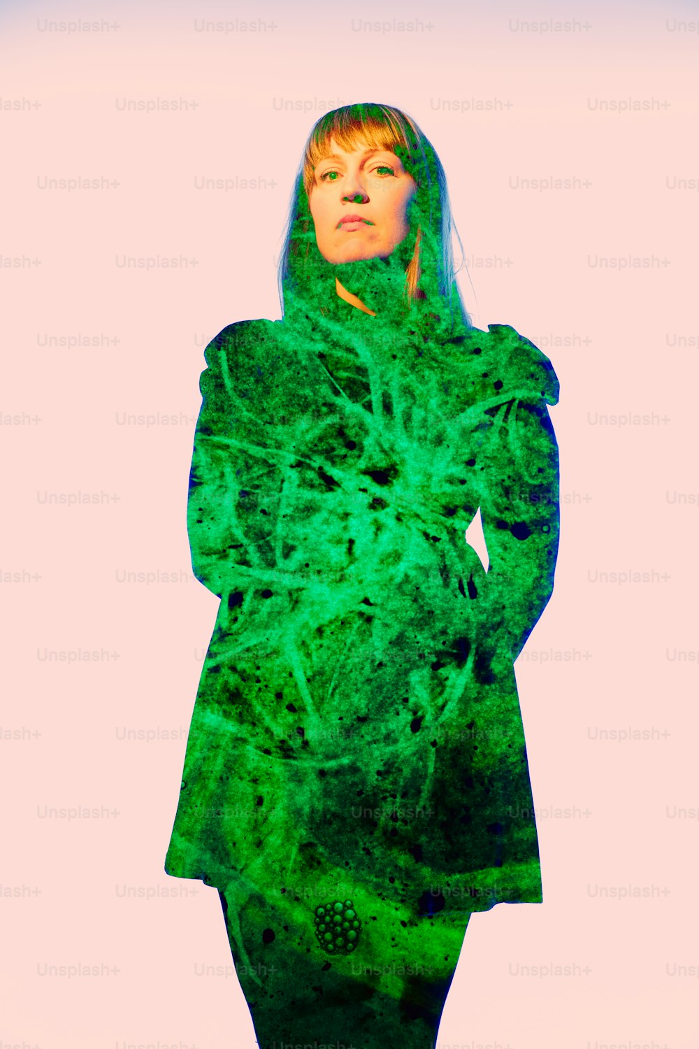 Uma mulher de casaco verde está de pé com as mãos nos quadris
