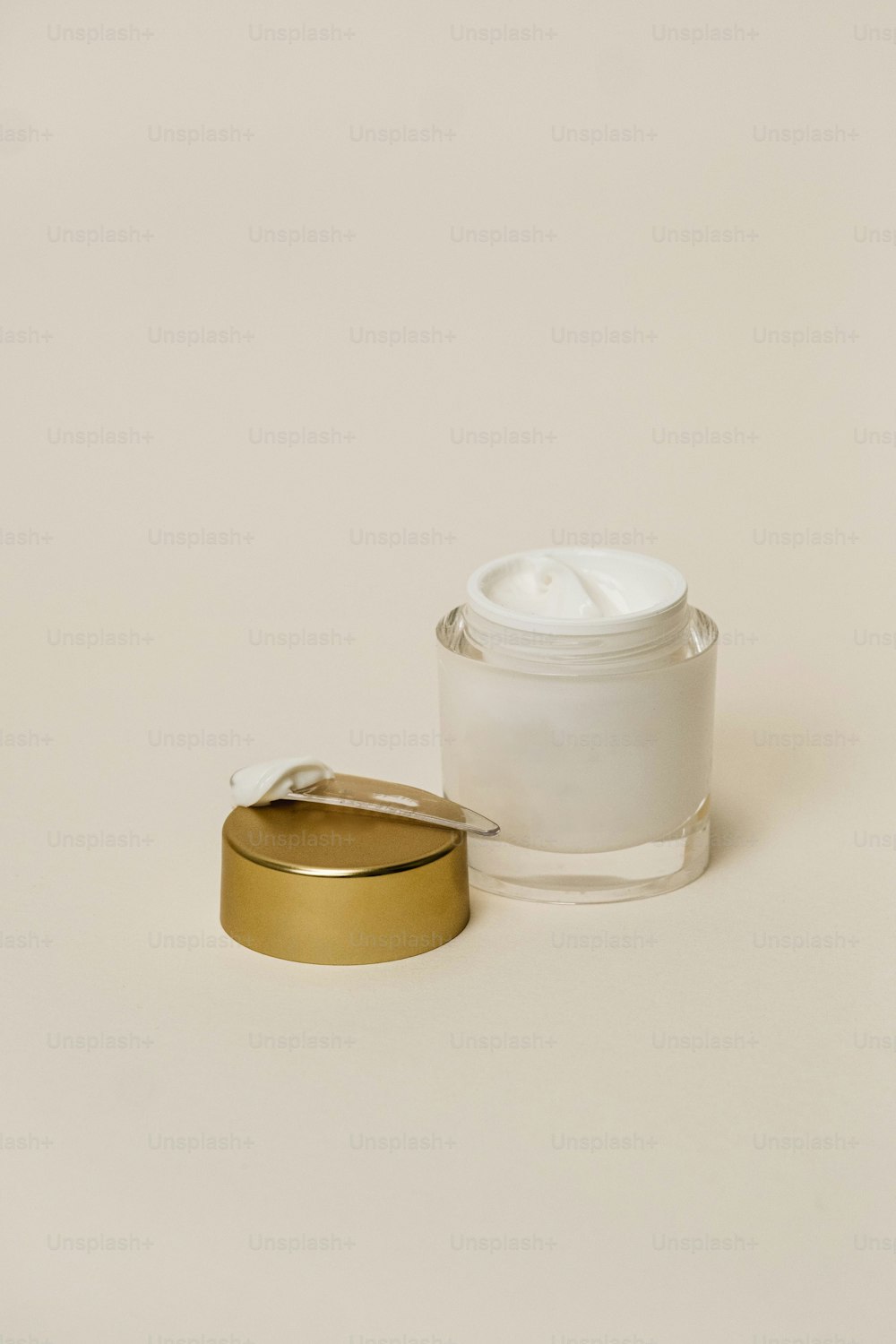 um recipiente branco com uma tampa dourada ao lado de um recipiente branco