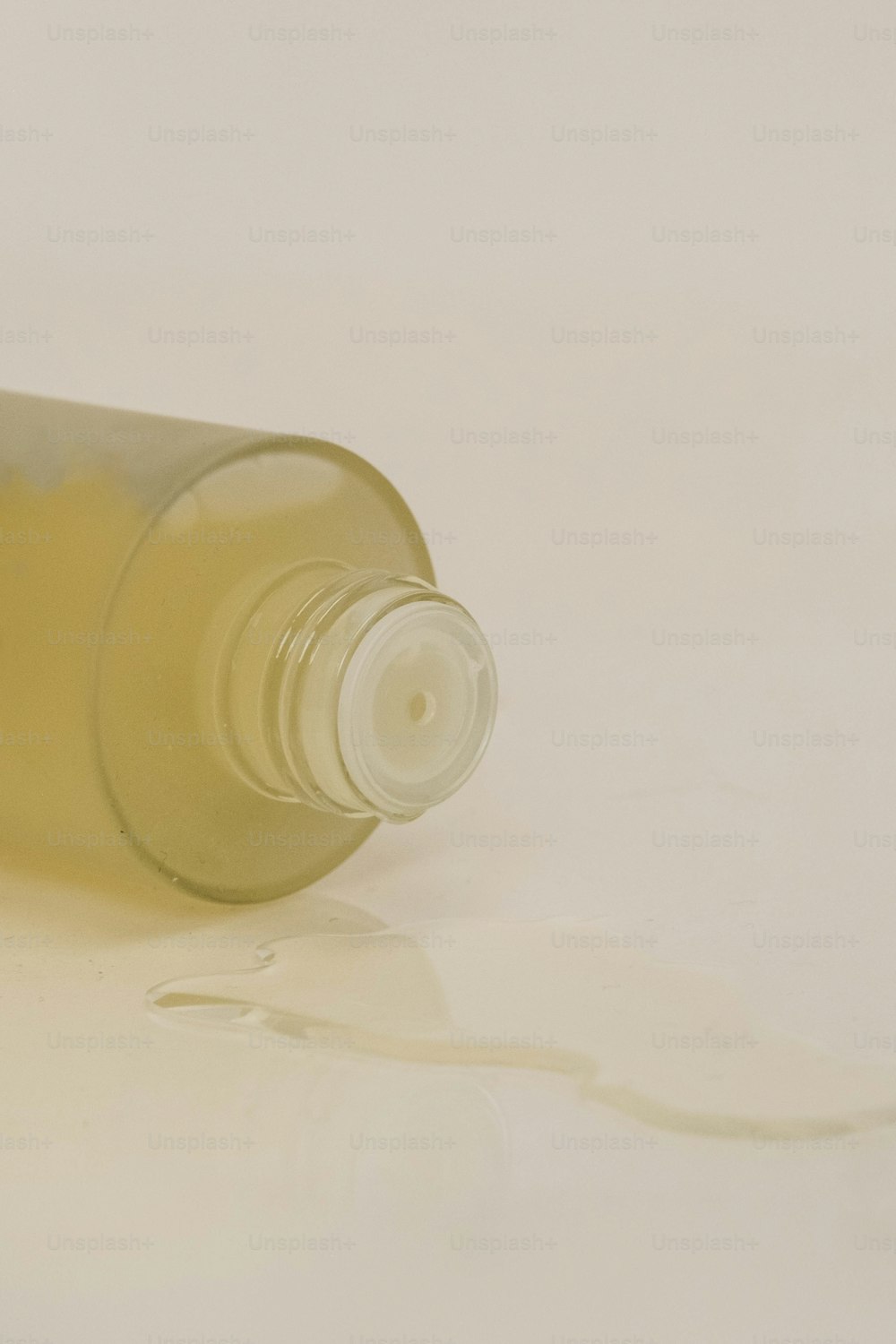 uma garrafa de líquido sentada em uma superfície branca