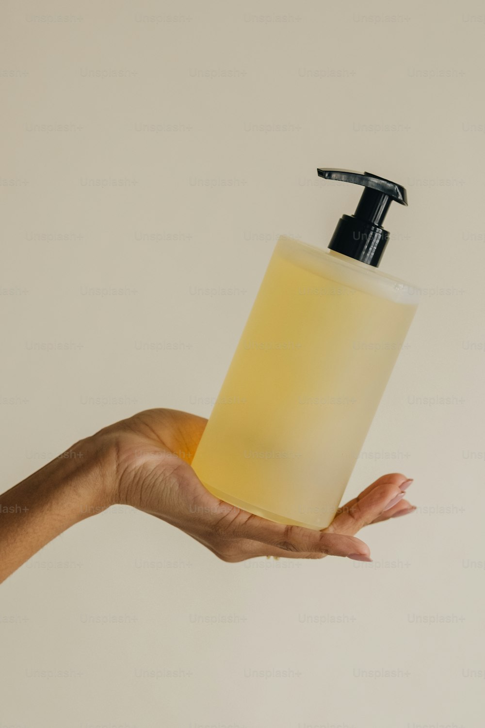 a hand holding a soap dispenser with a liquid in it