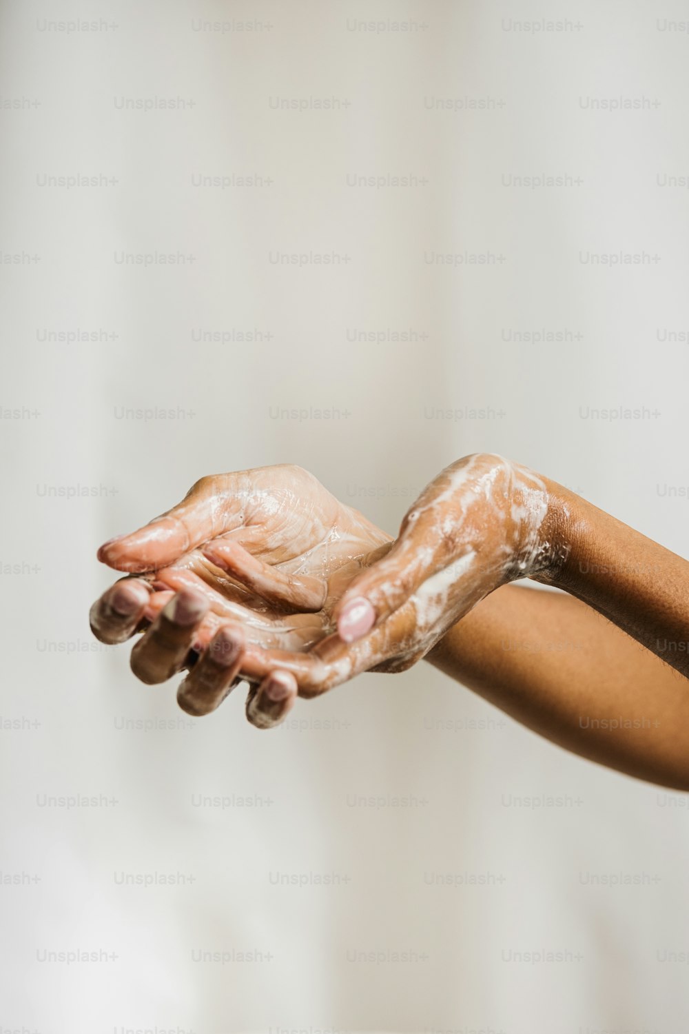 una mujer extendiendo sus manos con mucho jabón
