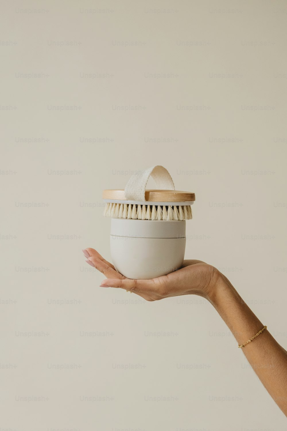 una mano sosteniendo un recipiente blanco con tapa de madera