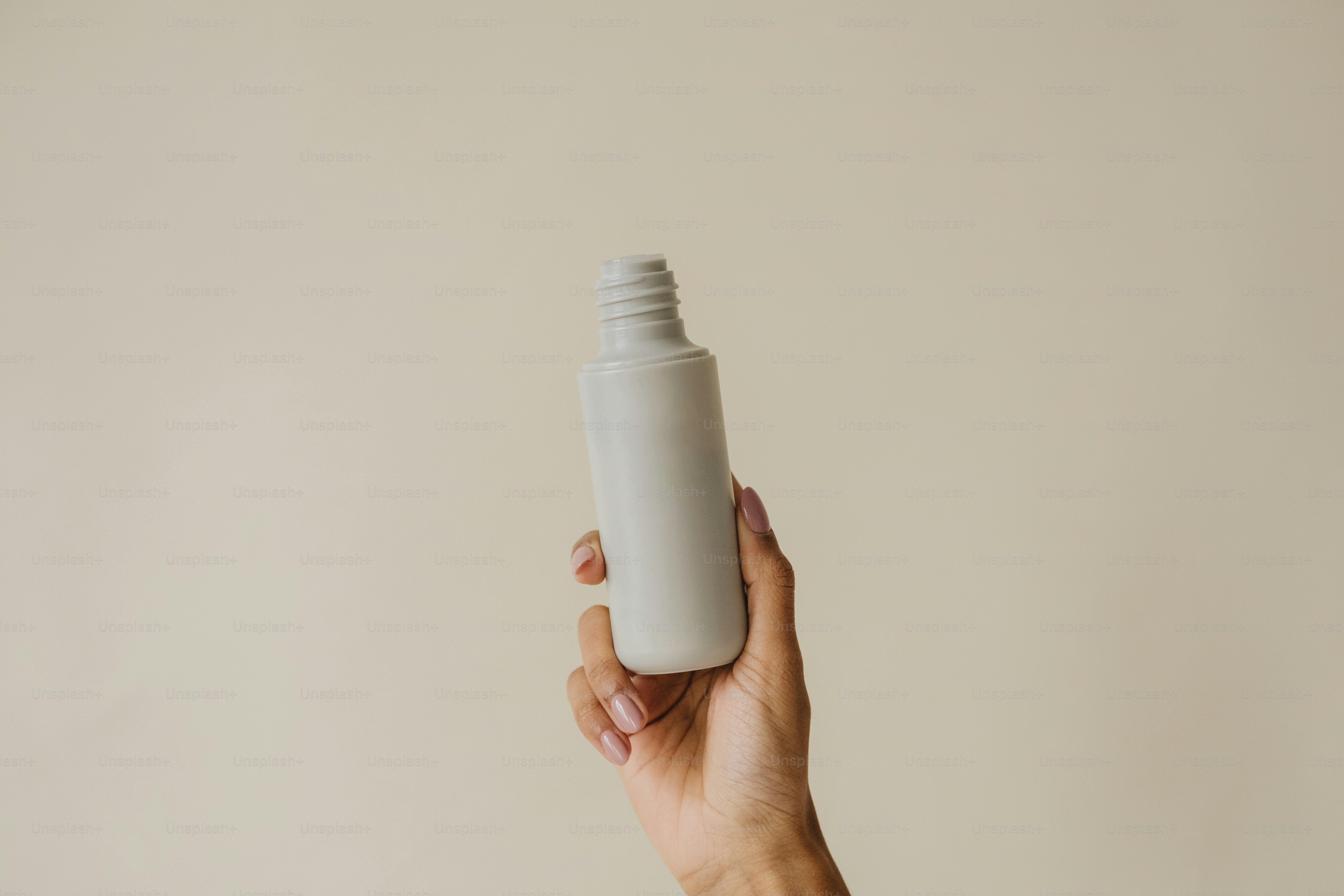 a person holding a white bottle in their hand