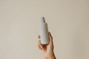a person holding a white bottle in their hand
